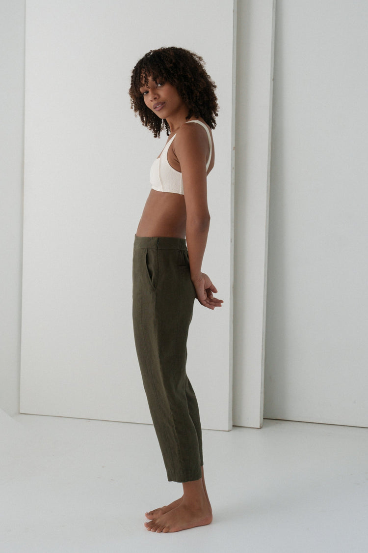 Emer Linen Pants in Khaki - side view, woman wearing Khaki tapered linen pants with ivory square-neck crop bra top, studio backdrop - Lilly Pilly Collection