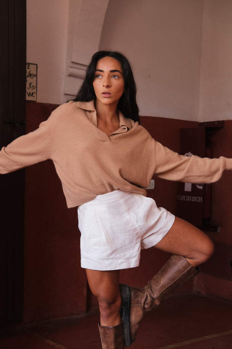 Emma Cashmere Knit in Camel Brown - front view, styled with ivory Gaia linen shorts, red wall background - Lilly Pilly Collection