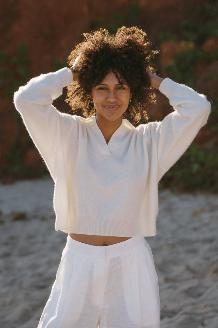Emma Cashmere Knit in Ivory - front view, hands in hair, worn with wide-leg trousers, beach backdrop - Lilly Pilly Collection