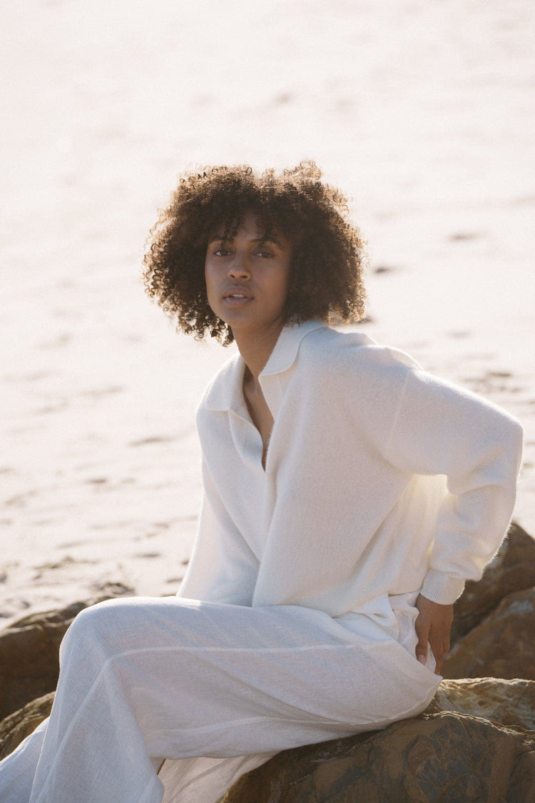 Emma Cashmere Knit in Ivory - sitting on beach rock, collared knit, worn with linen skirt - Lilly Pilly Collection