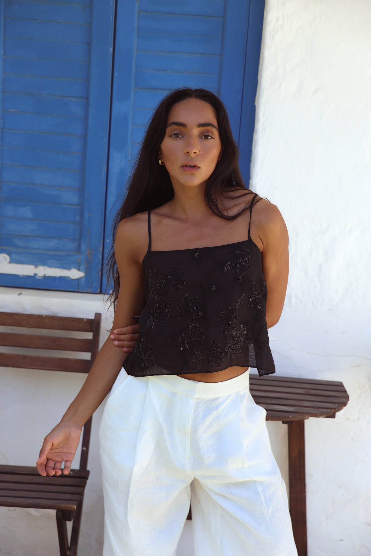 Flora Ramie Cami in Black - front view, floral embroidery and thin straps, worn with Oli Pants in Ivory, blue shutters backdrop - Lilly Pilly Collection