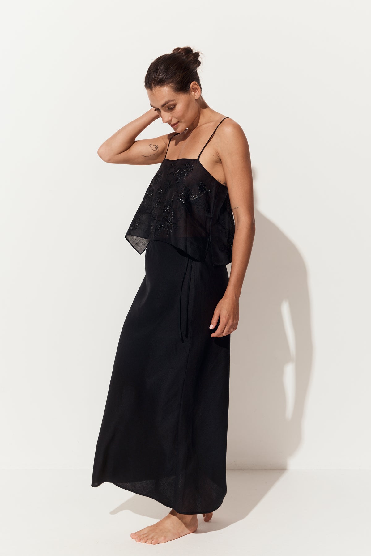 Flora Ramie Cami in Black - side view, hand to neck, styled with Riley Bias Linen Midi Skirt in Black, white studio - Lilly Pilly Collection