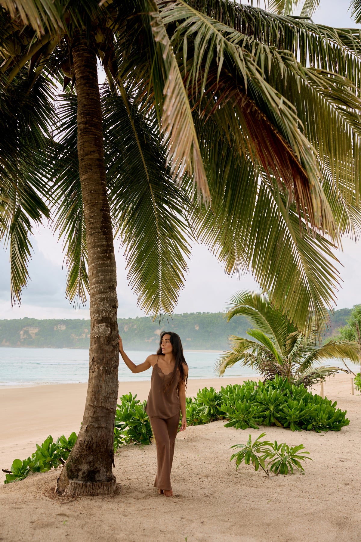 Frankie Silk Cami in Chocolate - full length, hand on palm tree, styled with matching linen maxi skirt, tropical beach - Lilly Pilly Collection