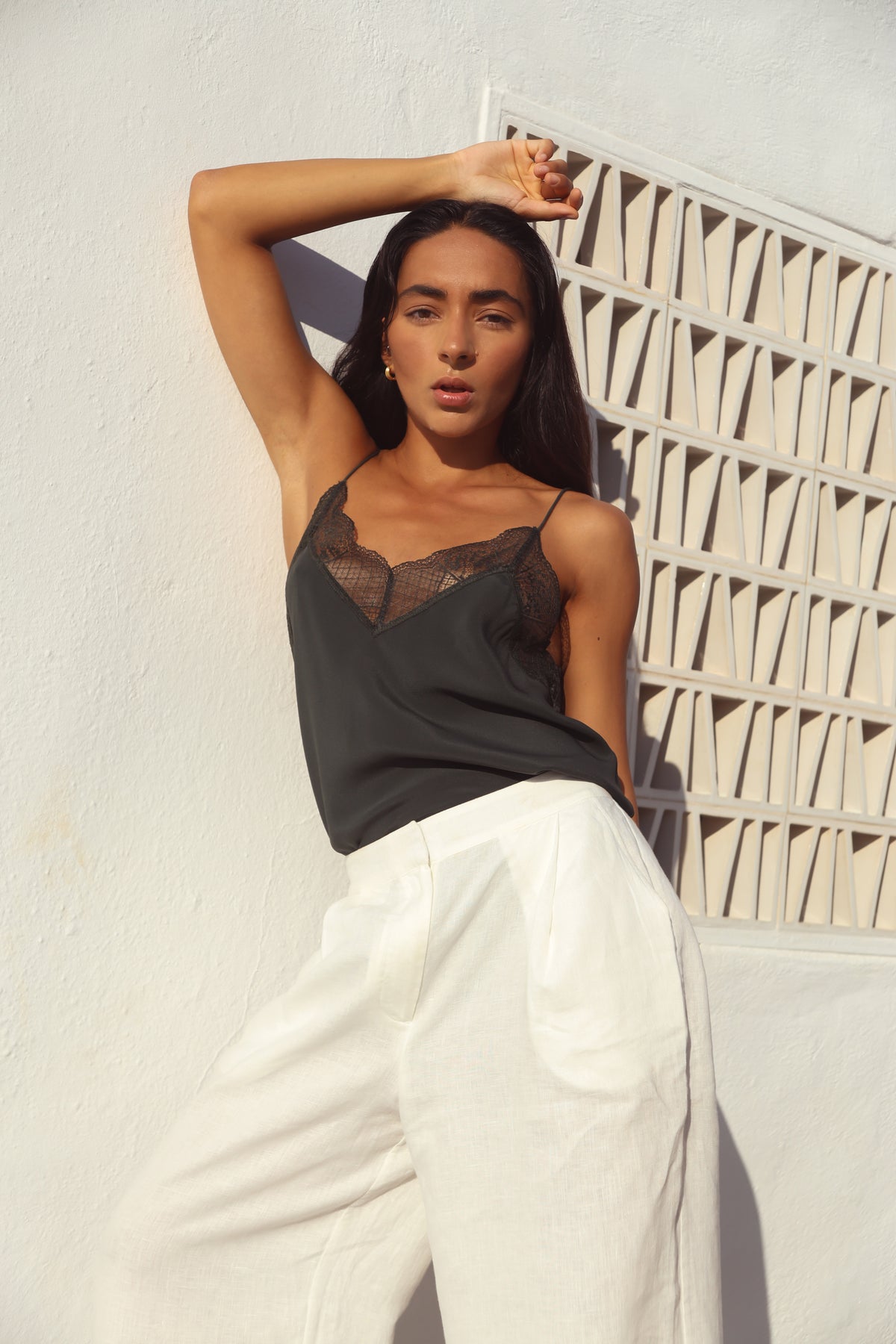 Frankie Silk Cami in Forest Green - arm raised, V-neckline with lace trim, styled with ivory Oli Linen Pants, whitewashed wall - Lilly Pilly Collection
