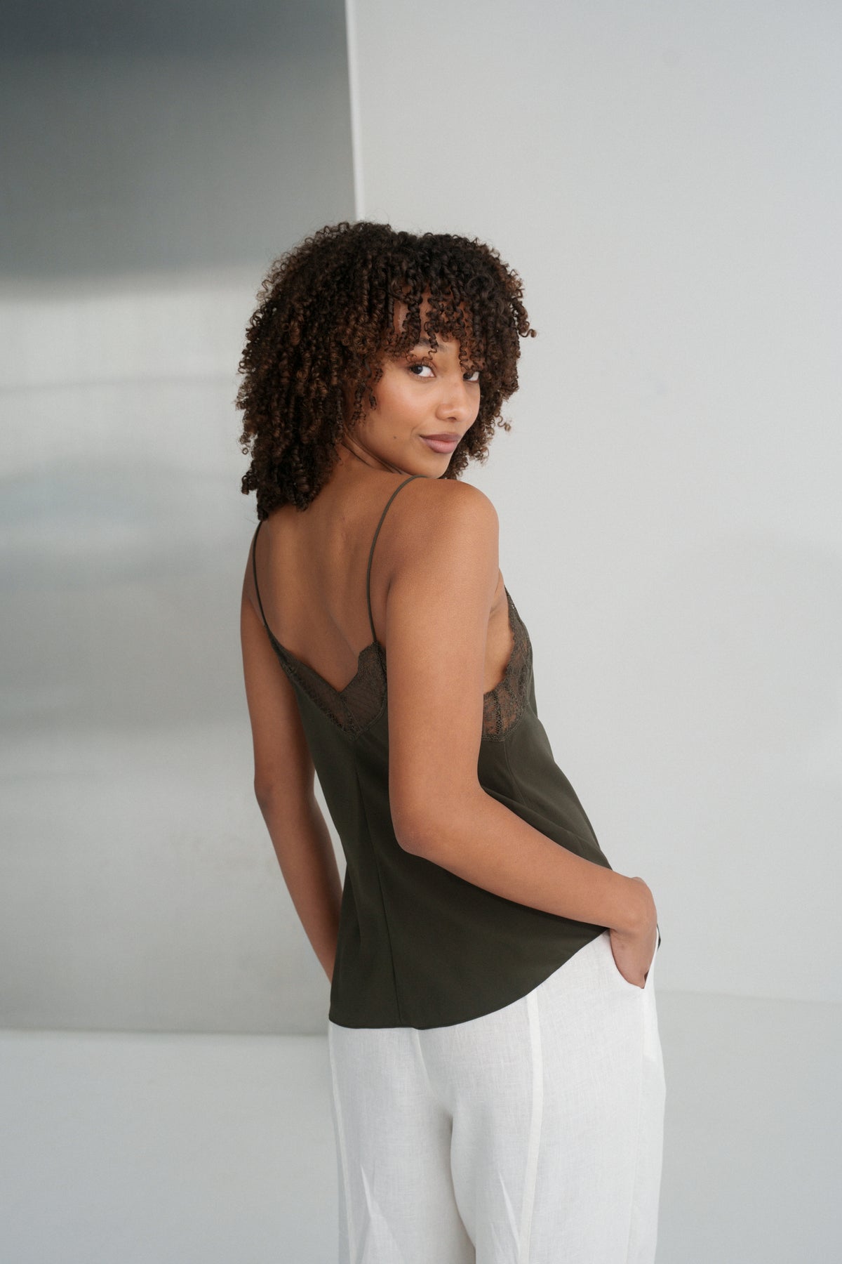 LILLY PILLY woman wearing Frankie silk cami in khaki  and ivory Oli linen pants