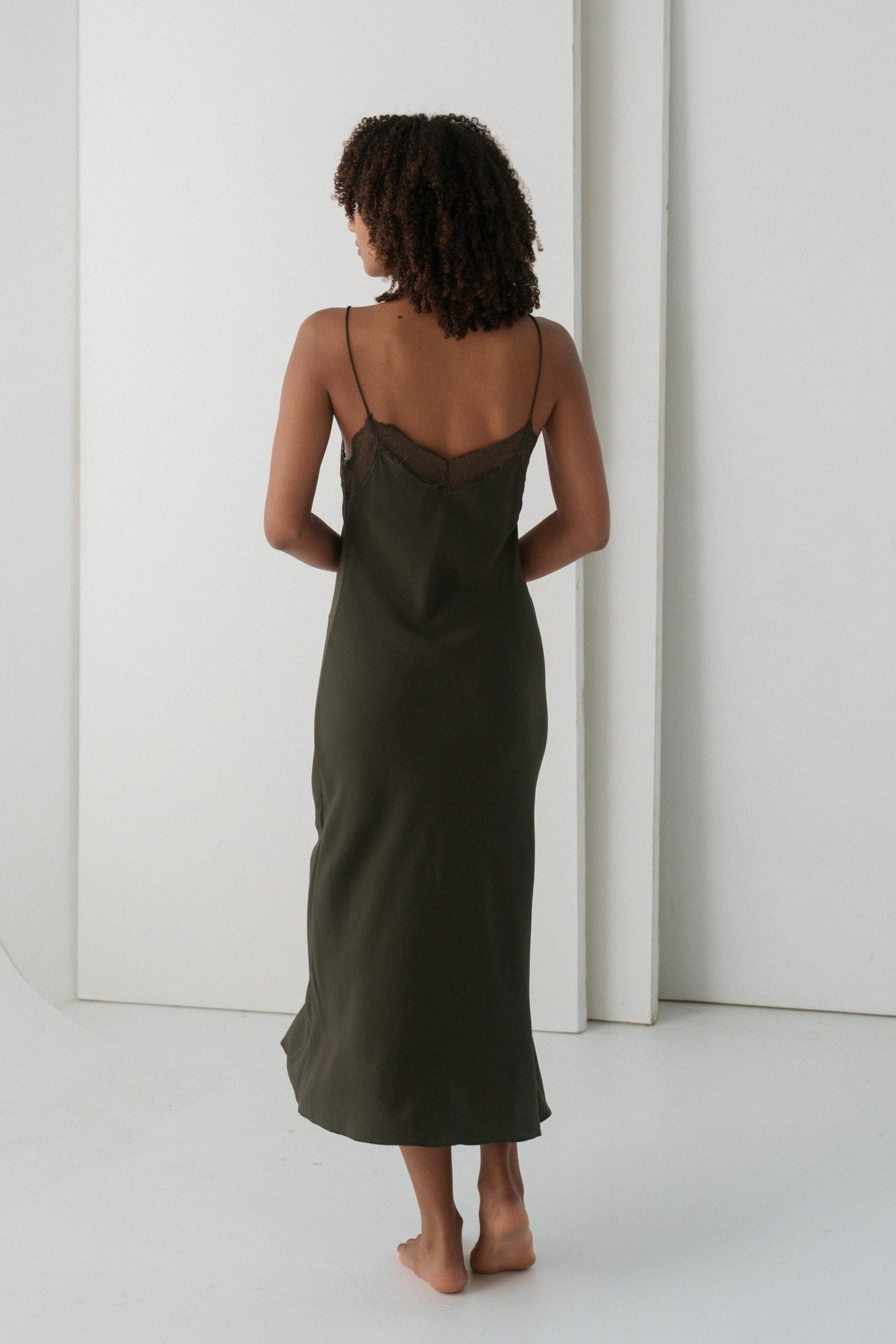 Woman wearing a khaki Freya silk slip dress with lace details showing back view
