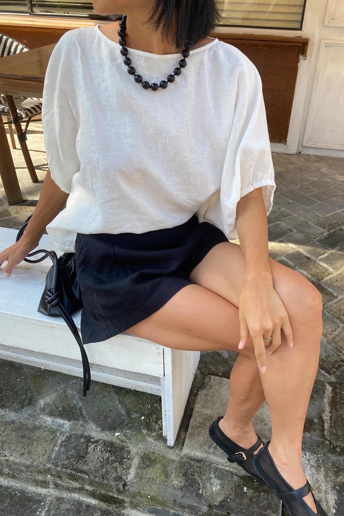 Gaia Linen Shorts in Black - close up side view seated with Demi ivory linen top - Lilly Pilly Collection