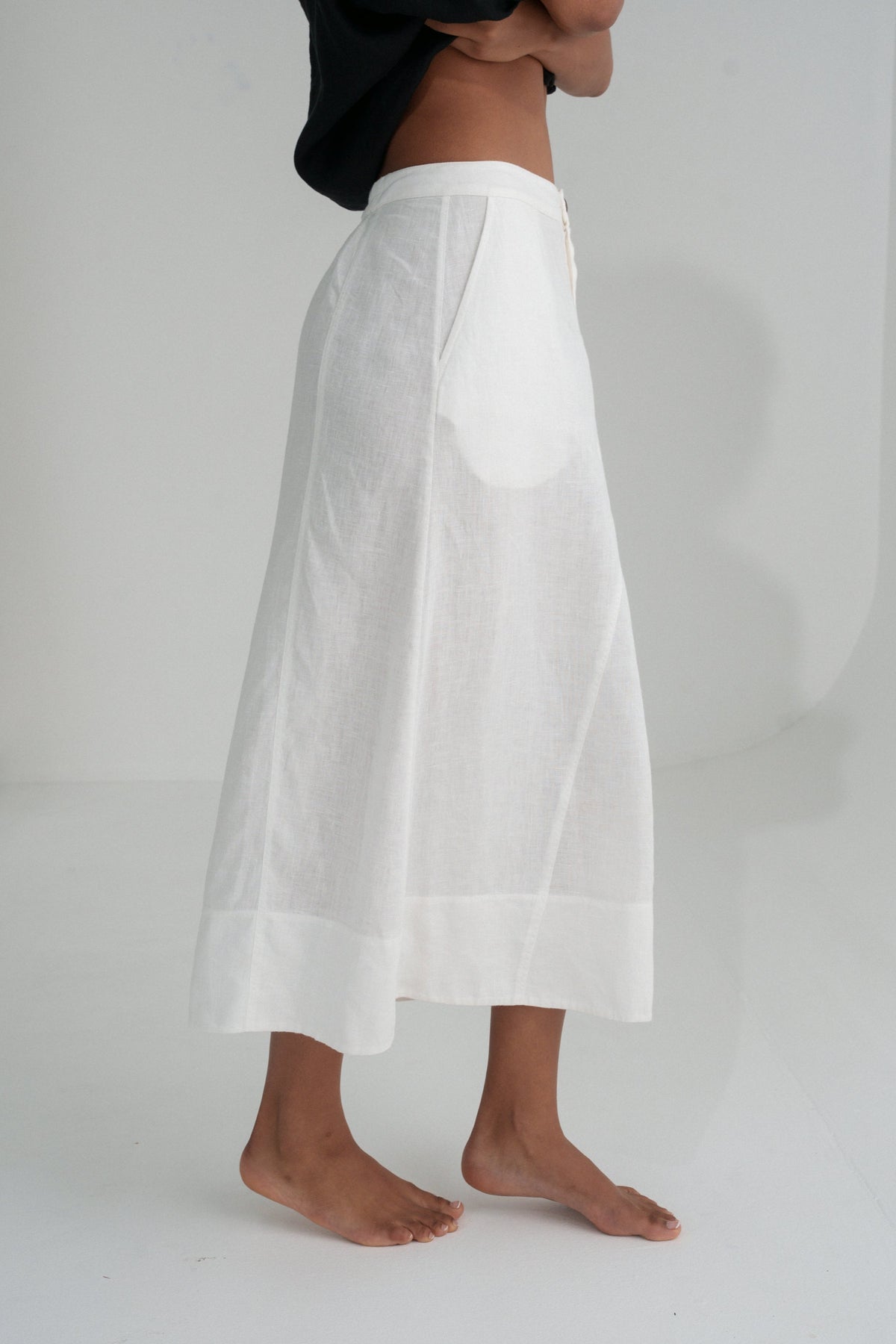 Close up side view of woman wearing  a LILLY PILLY Gia linen skirt in Ivory with a white background