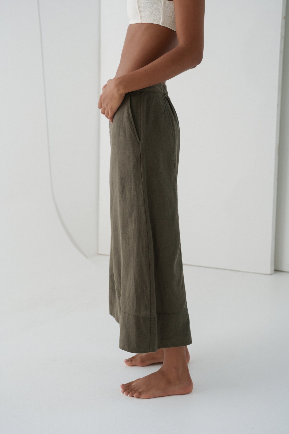 Side view close up of woman wearing  khaki green Gia linen skirt against a white background