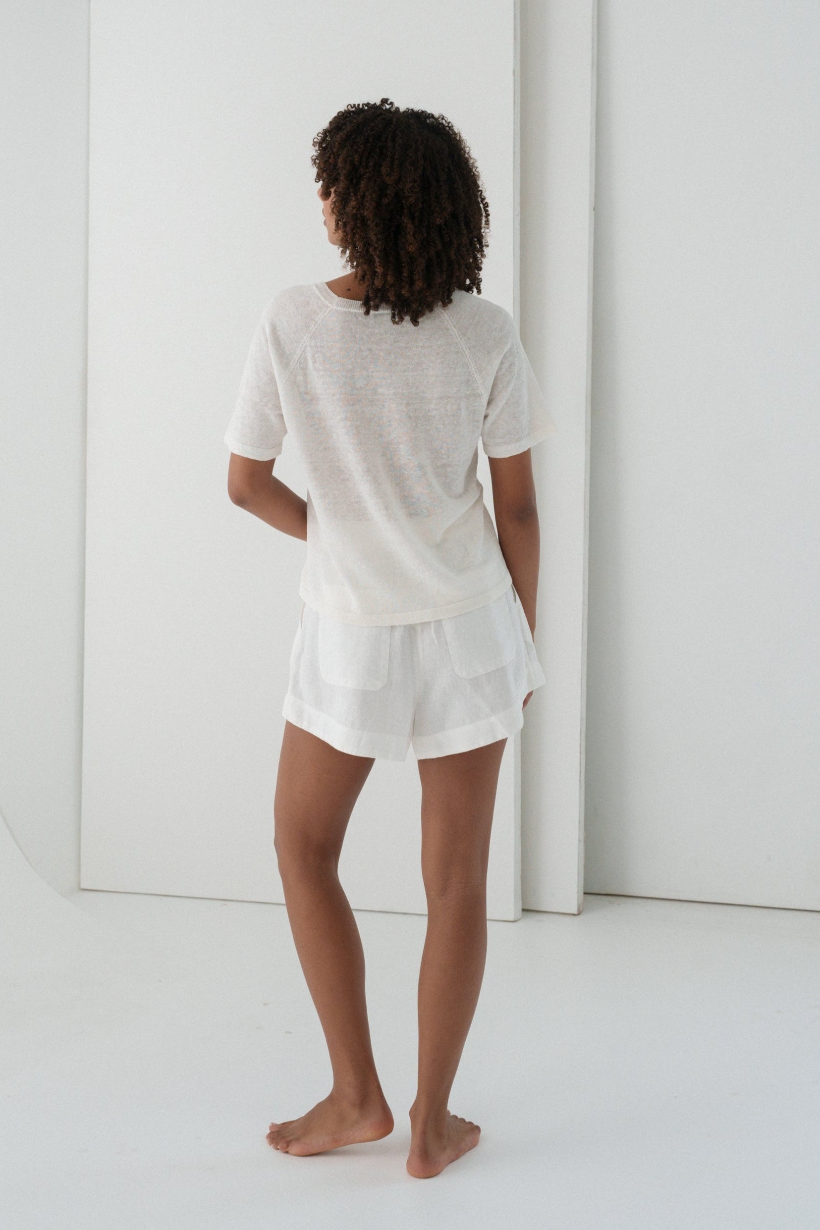 Person wearing a Grace knit top in Ivory and Gaia ivory shorts set in a minimalistic setting