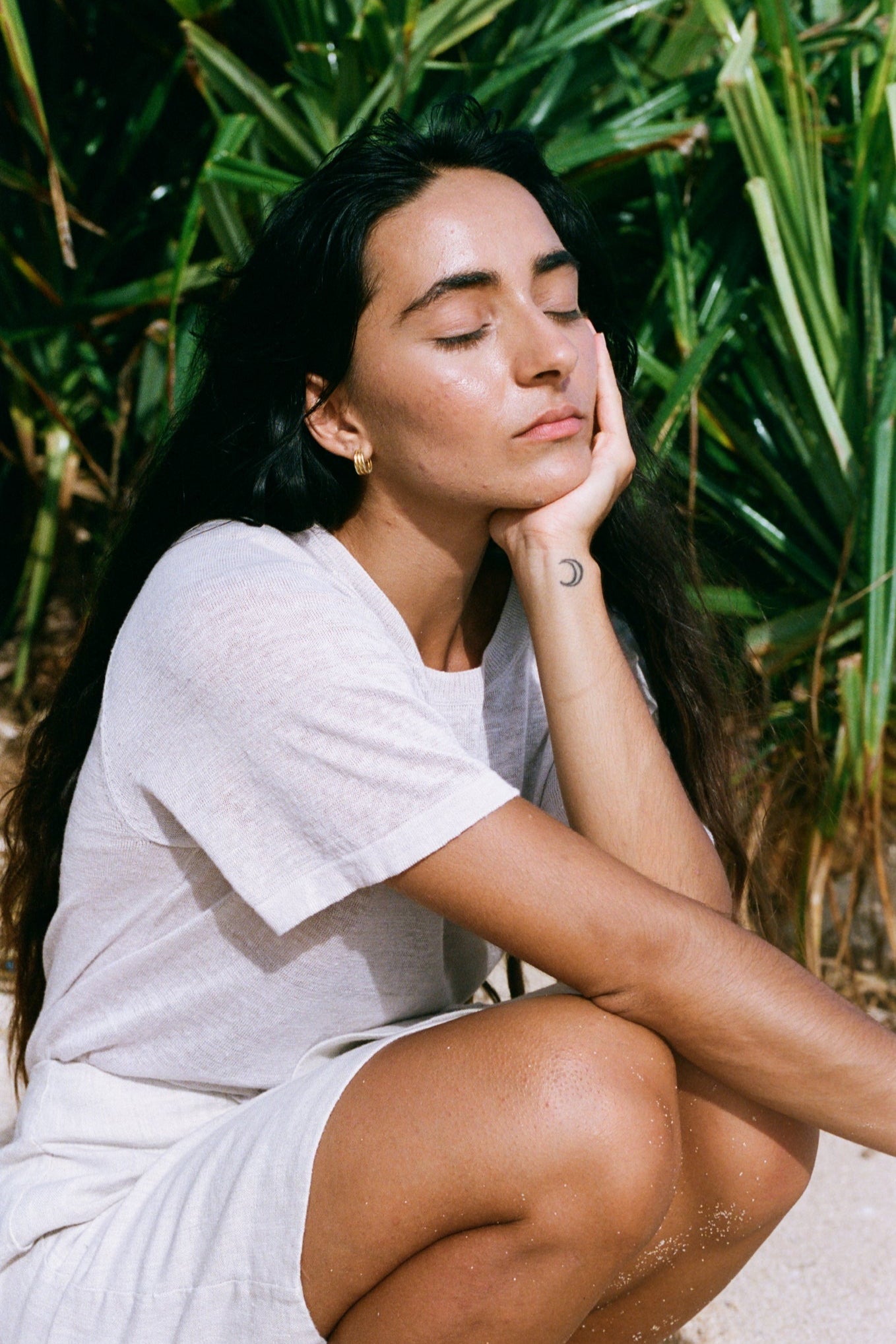 Woman wearing Grace linen knit top sitting outdoors with greenery in the background