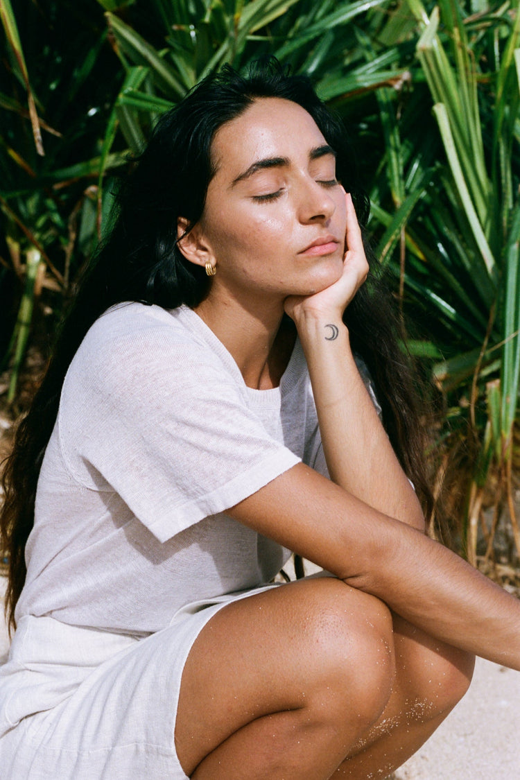Grace Linen Knit Top in Oatmeal - woman seated outdoors, crew neckline and short sleeves, tropical greenery backdrop - Lilly Pilly Collection