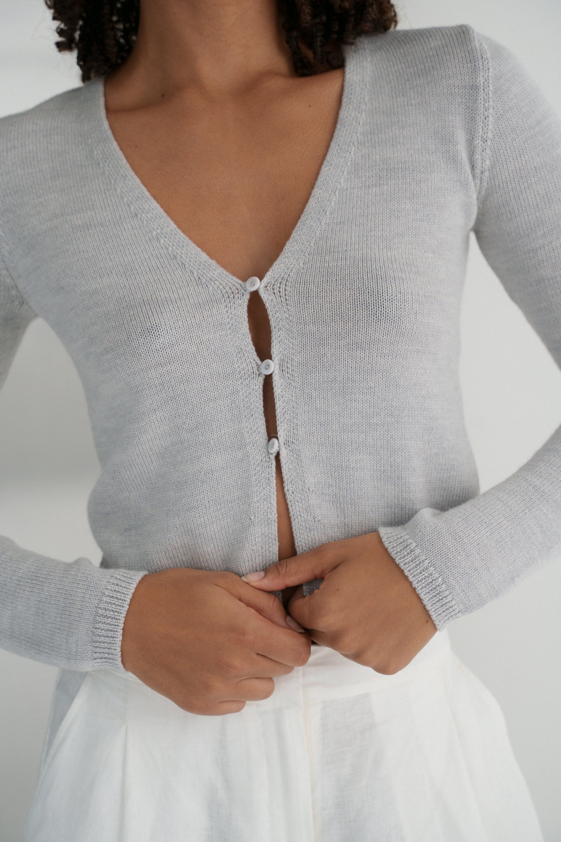 Close up of LILLY PILLY woman wearing a fog gray Indie merino wool cardigan in front of a white background