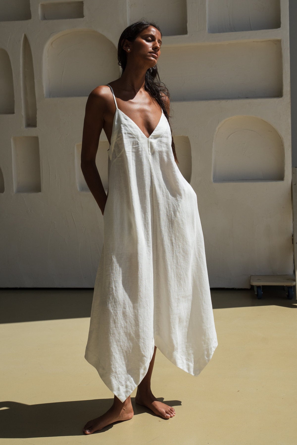 Woman wearing a ivory white Inez linen dress standing against a neutral background