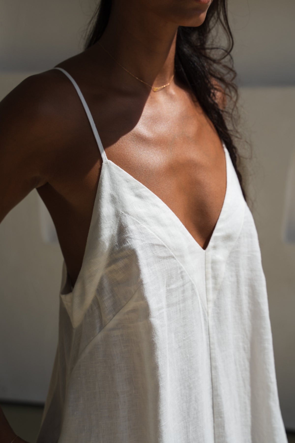 Close up view of a woman wearing a ivory white Inez linen dress standing against a neutral background