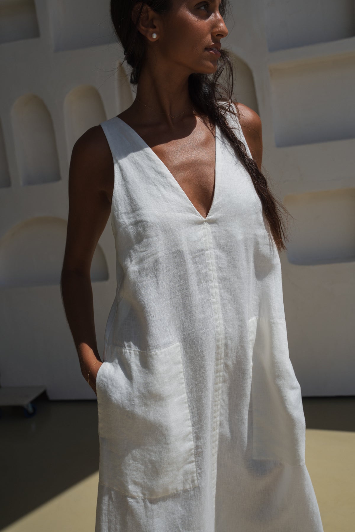 Woman wearing an ivory white LILLY PILLY Iris dress in a minimal indoor setting