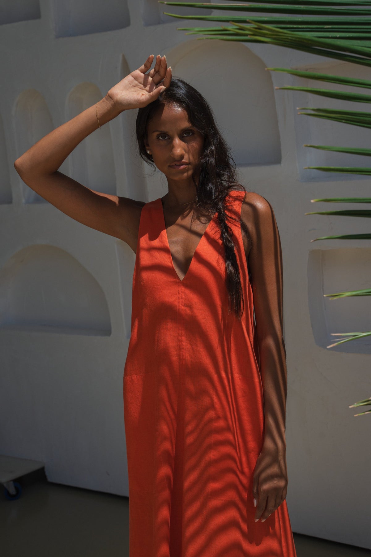 LILLY PILLY woman wearing a spritz Iris dress against a white wall with greenery.