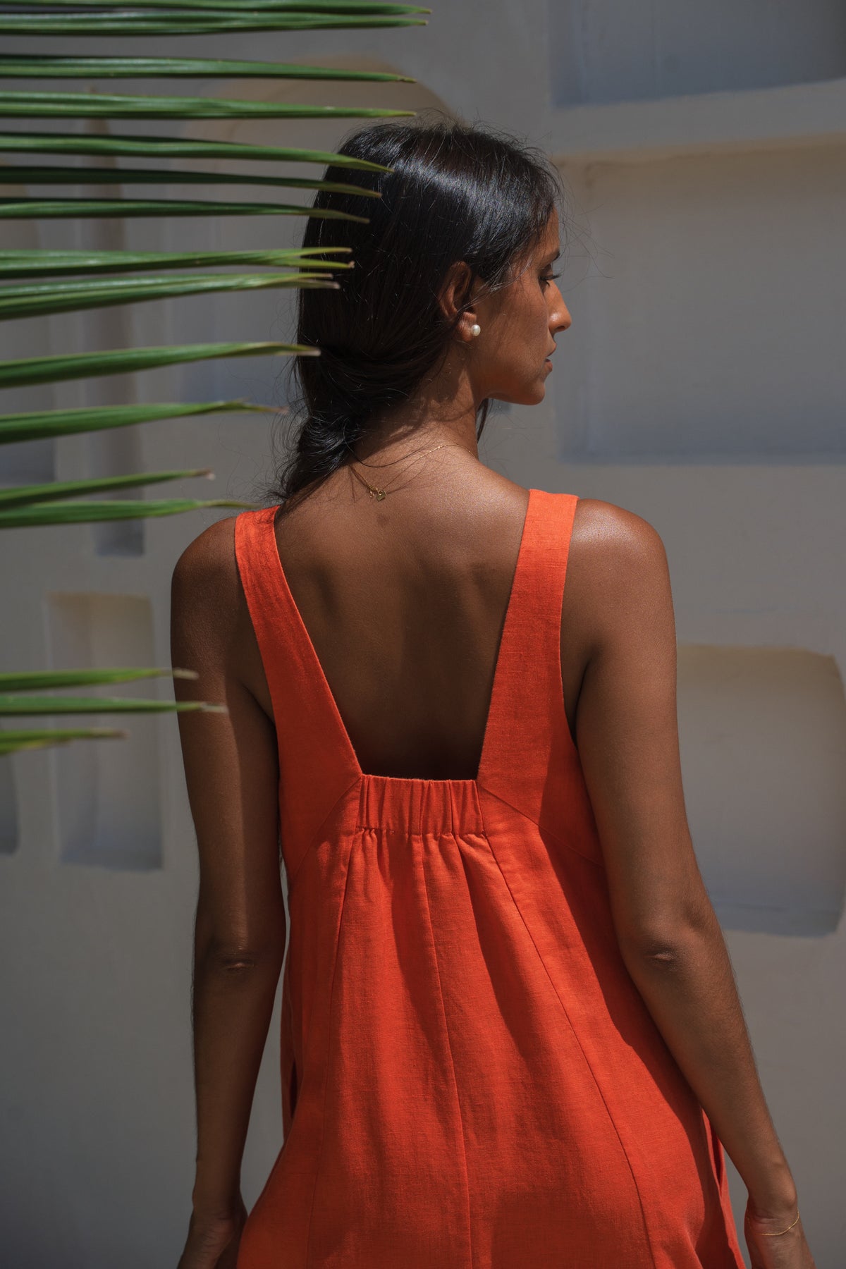 LILLY PILLY woman wearing a spritz Iris dress showing back view with a plant in the background