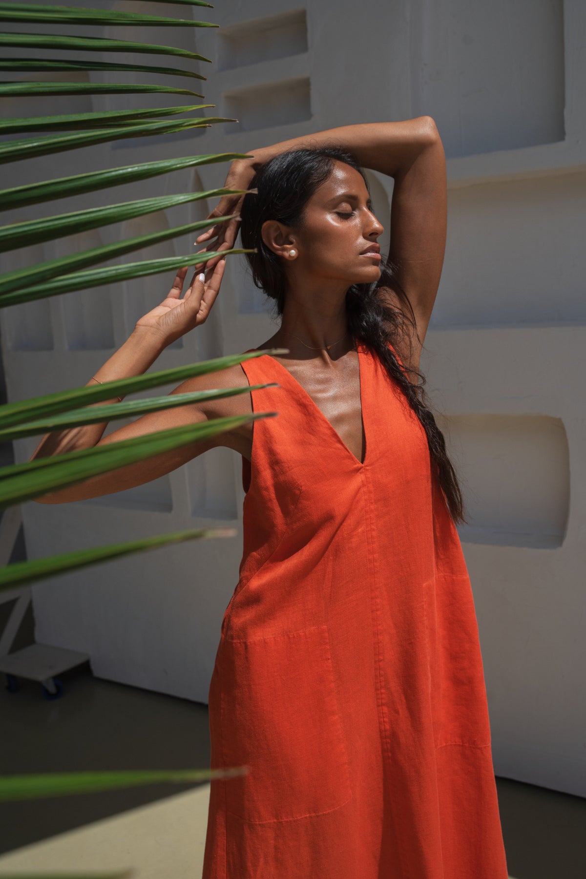 LILLY PILLY woman wearing a spritz Iris dress holding a plant in a minimal indoor setting