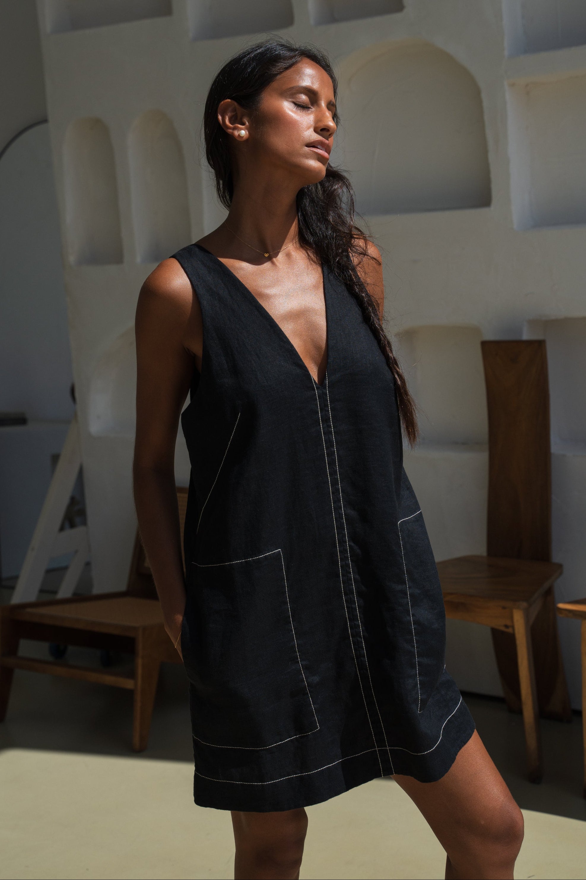 LILLY PILLY woman wearing a black Azalea linen dress in a minimal indoor setting