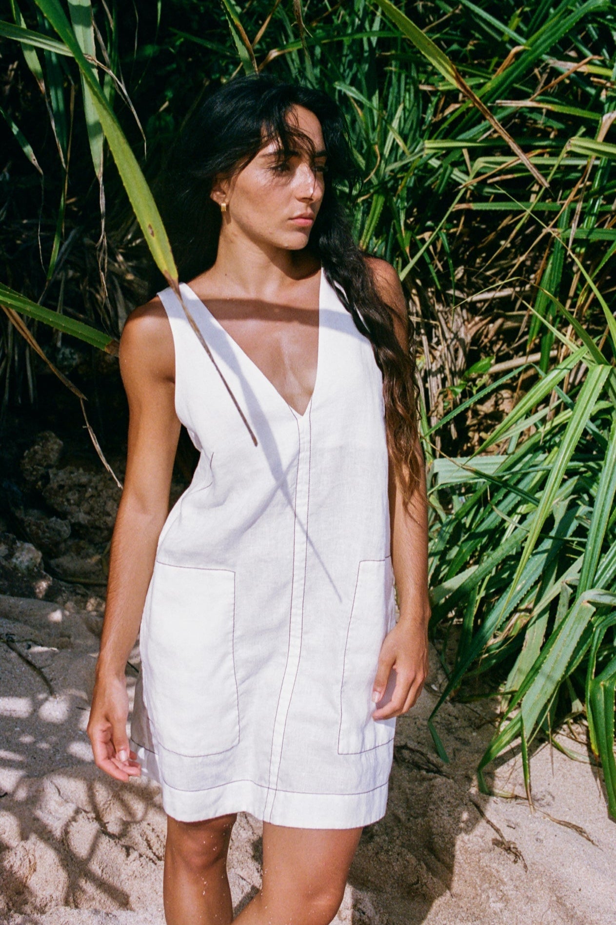 LILLY PILLY woman in an ivory Isla linen dress standing in a natural setting with greenery