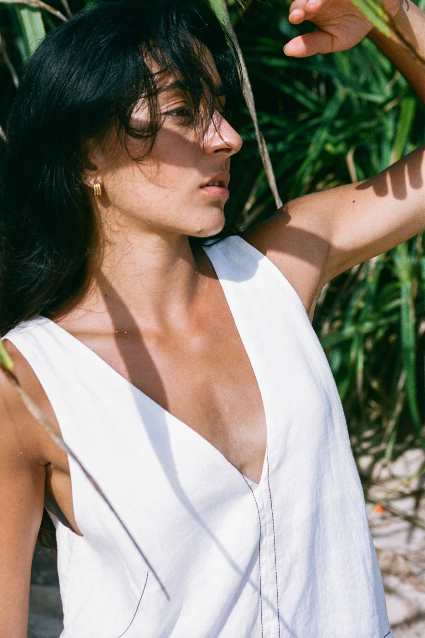 Close up of LILLY PILLY woman in an ivory Isla linen dress standing in a natural setting with greenery