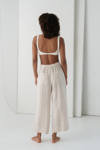 Ivy Linen Crop Pants in Oatmeal - back view showing elasticated waistband and wide-leg linen silhouette, woman wearing ivory square-neck crop bra top, white studio backdrop - Lilly Pilly Collection