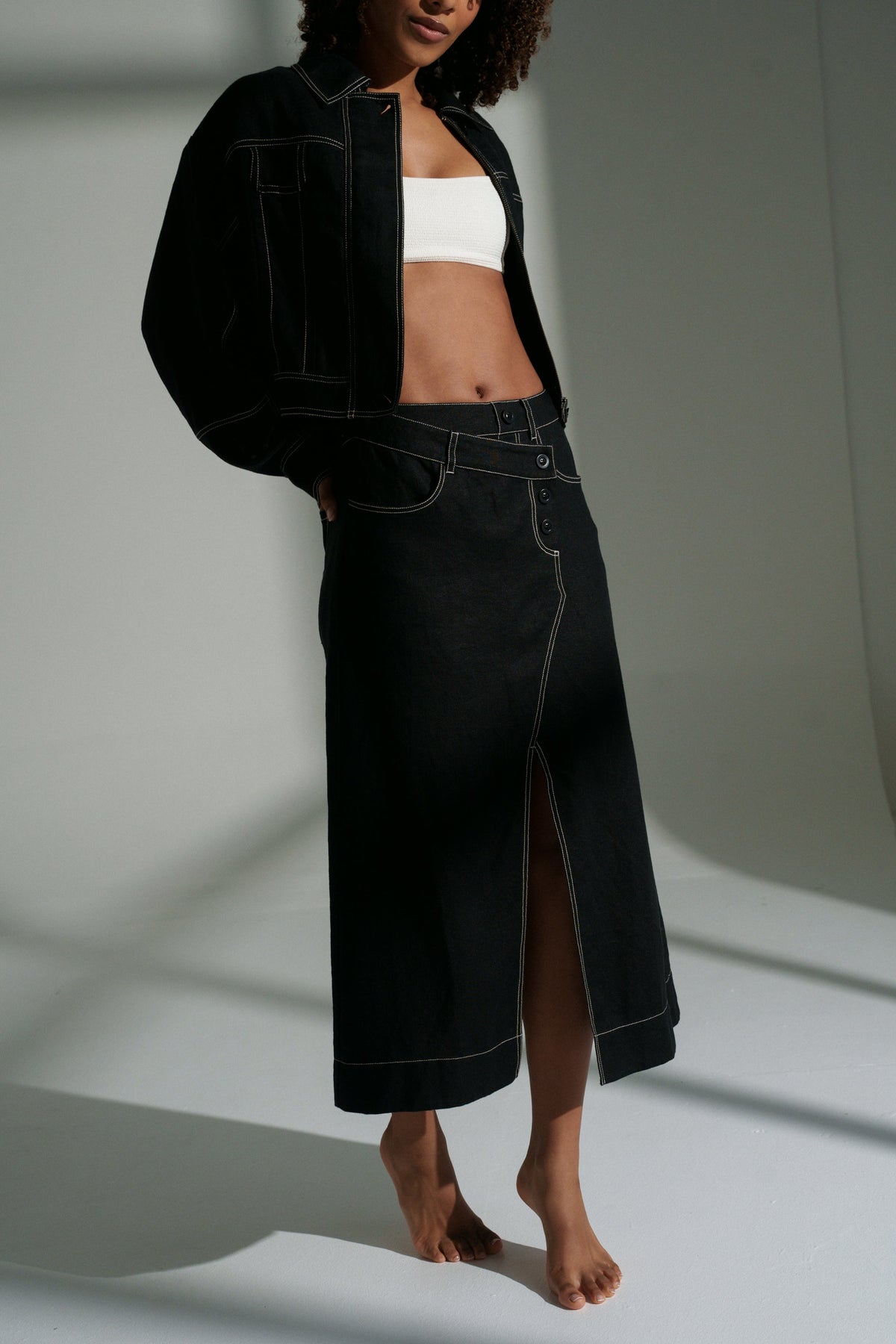 LILLY PILLY woman wearing a black Wes linen jacket and Jax linen skirt on a white background