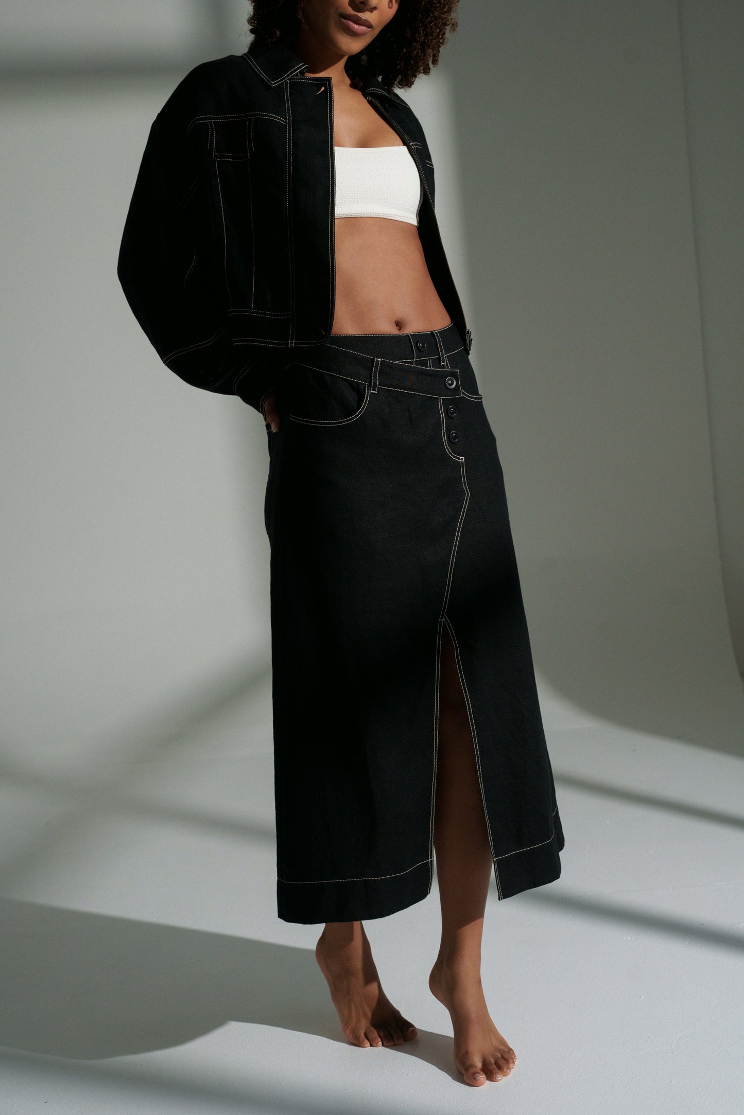 LILLY PILLY woman wearing a black Wes linen jacket and Jax linen skirt on a white background