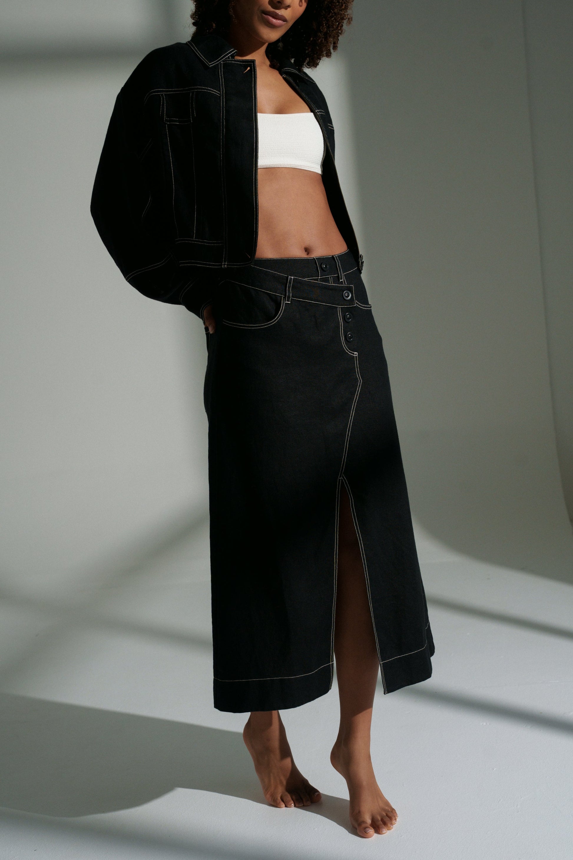 LILLY PILLY woman wearing a black Wes linen jacket and Jax linen skirt on a white background