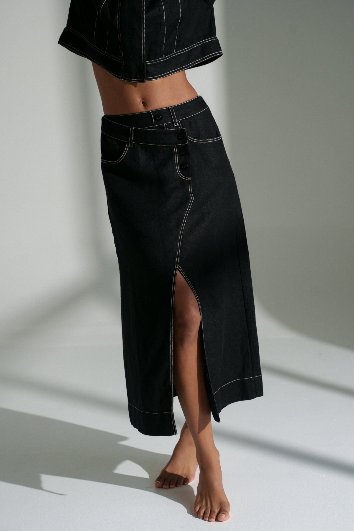 LILLY PILLY woman wearing a black Wes linen jacket and Jax linen skirt on a white background
