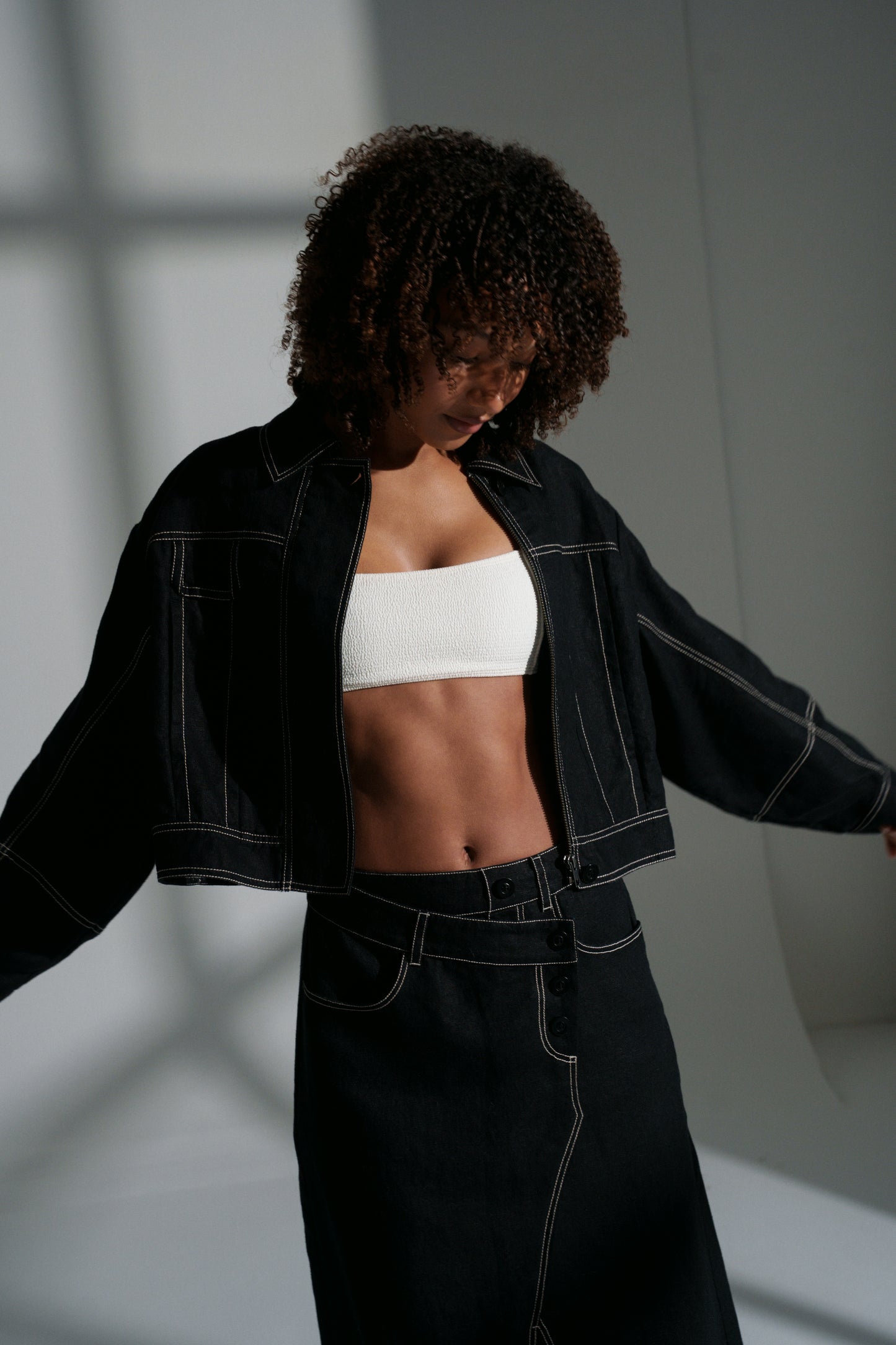 LILLY PILLY woman wearing a black Wes linen jacket and Jax linen skirt with a white top against a neutral background