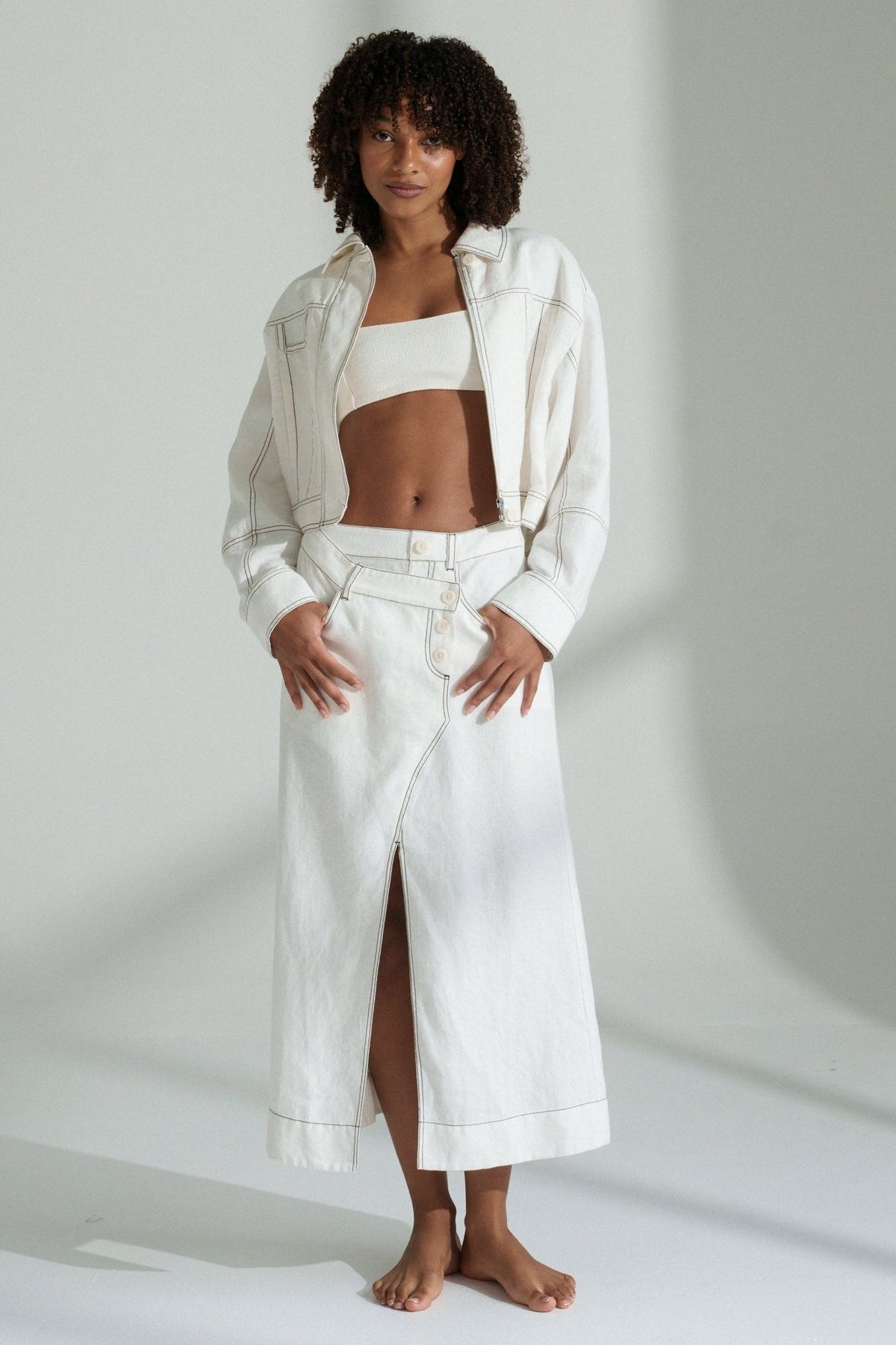 LILLY PILLY woman in a ivory Jax Skirt with Wes jacket outfit standing against a plain background