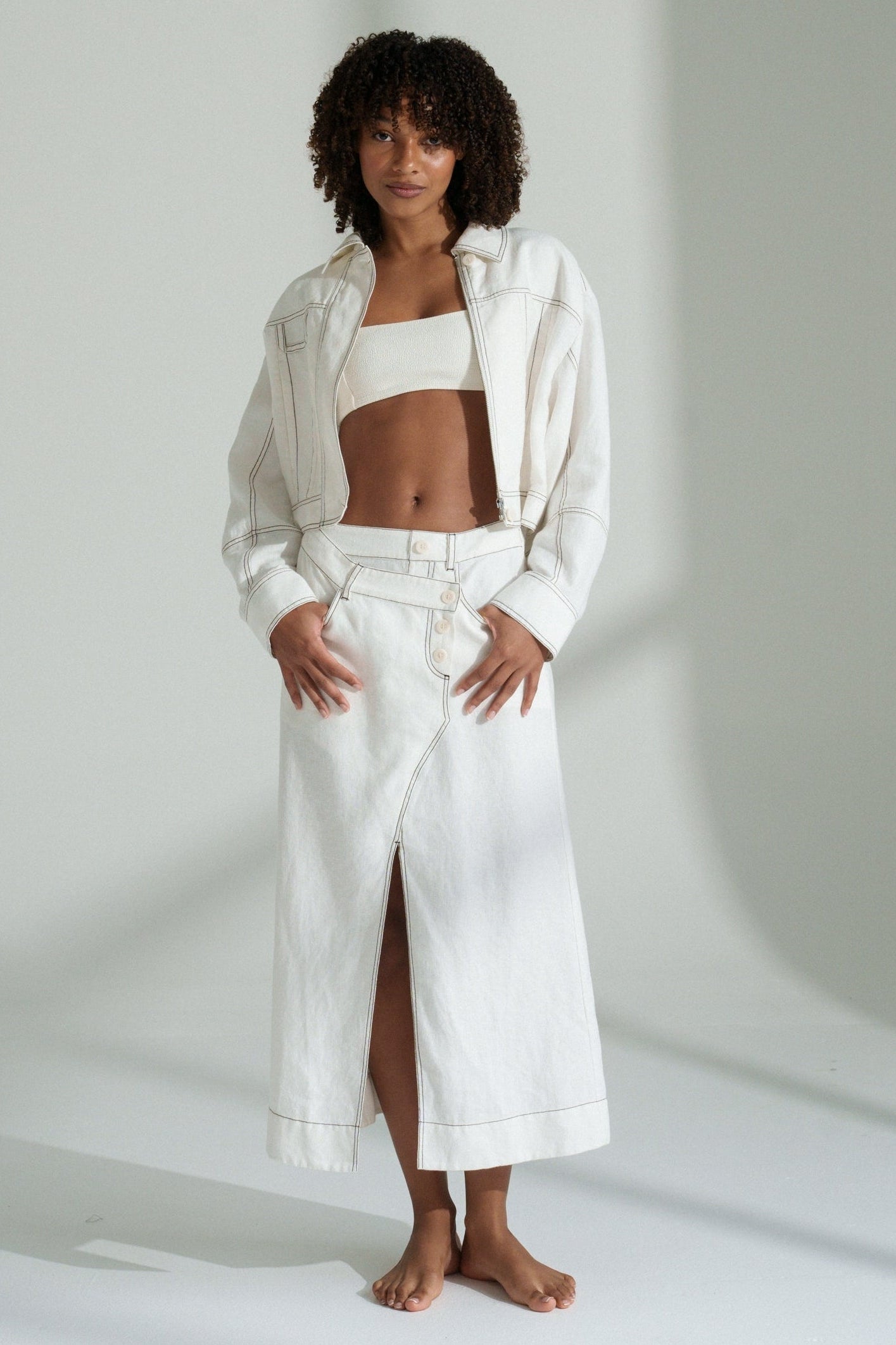 LILLY PILLY woman in a ivory Jax Skirt with Wes jacket outfit standing against a plain background