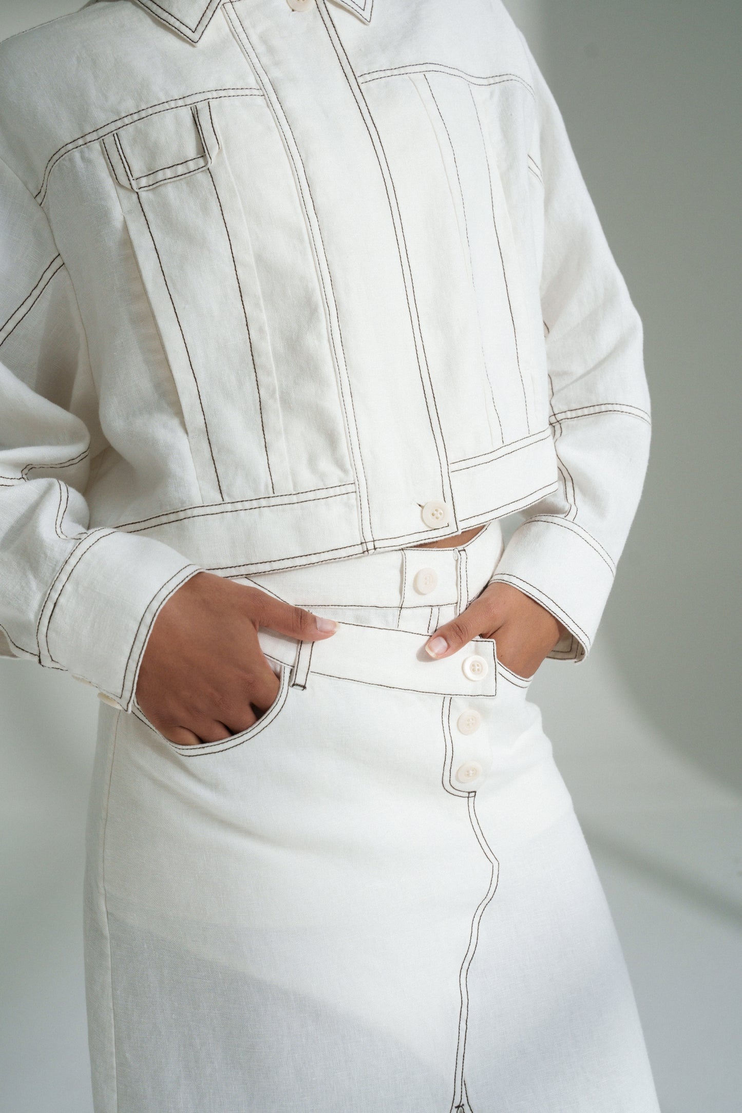 LILLY PILLY woman in a ivory Jax Skirt and Wes jacket  with visible stitching on a plain background