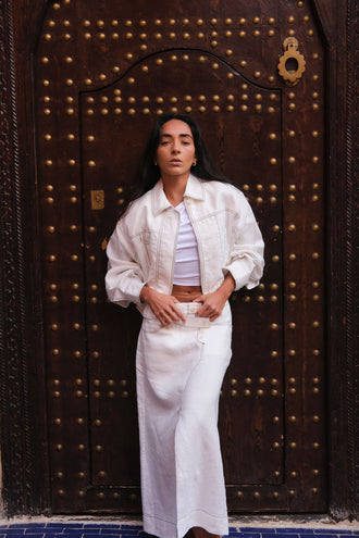 Jax Linen Midi Skirt in Ivory - front view, styled with the Wes jacket, standing in front of a large wooden door with metallic studs - Lilly Pilly Collection