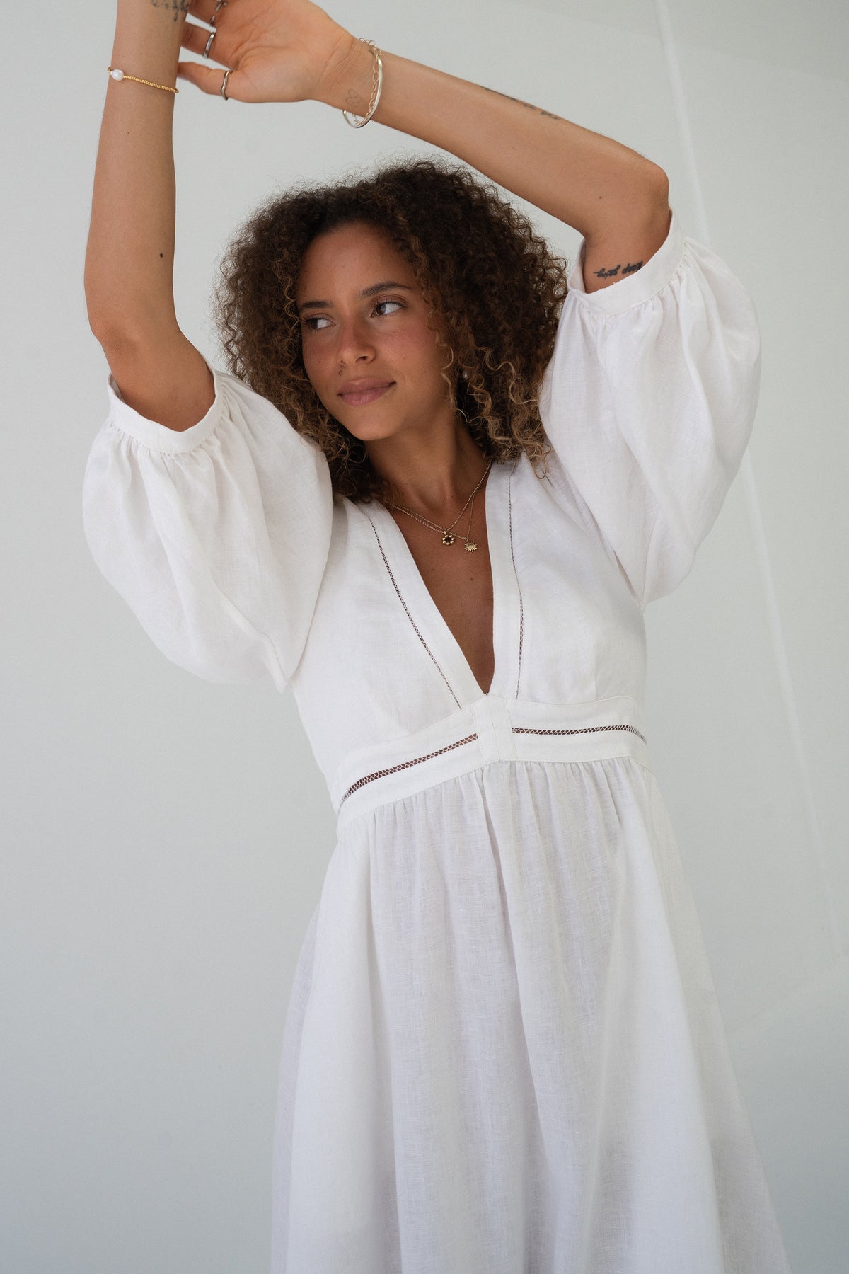 Josie Linen Midi Dress in Ivory - model with arms raised showing puff sleeve volume and V-neckline - Lilly Pilly Collection