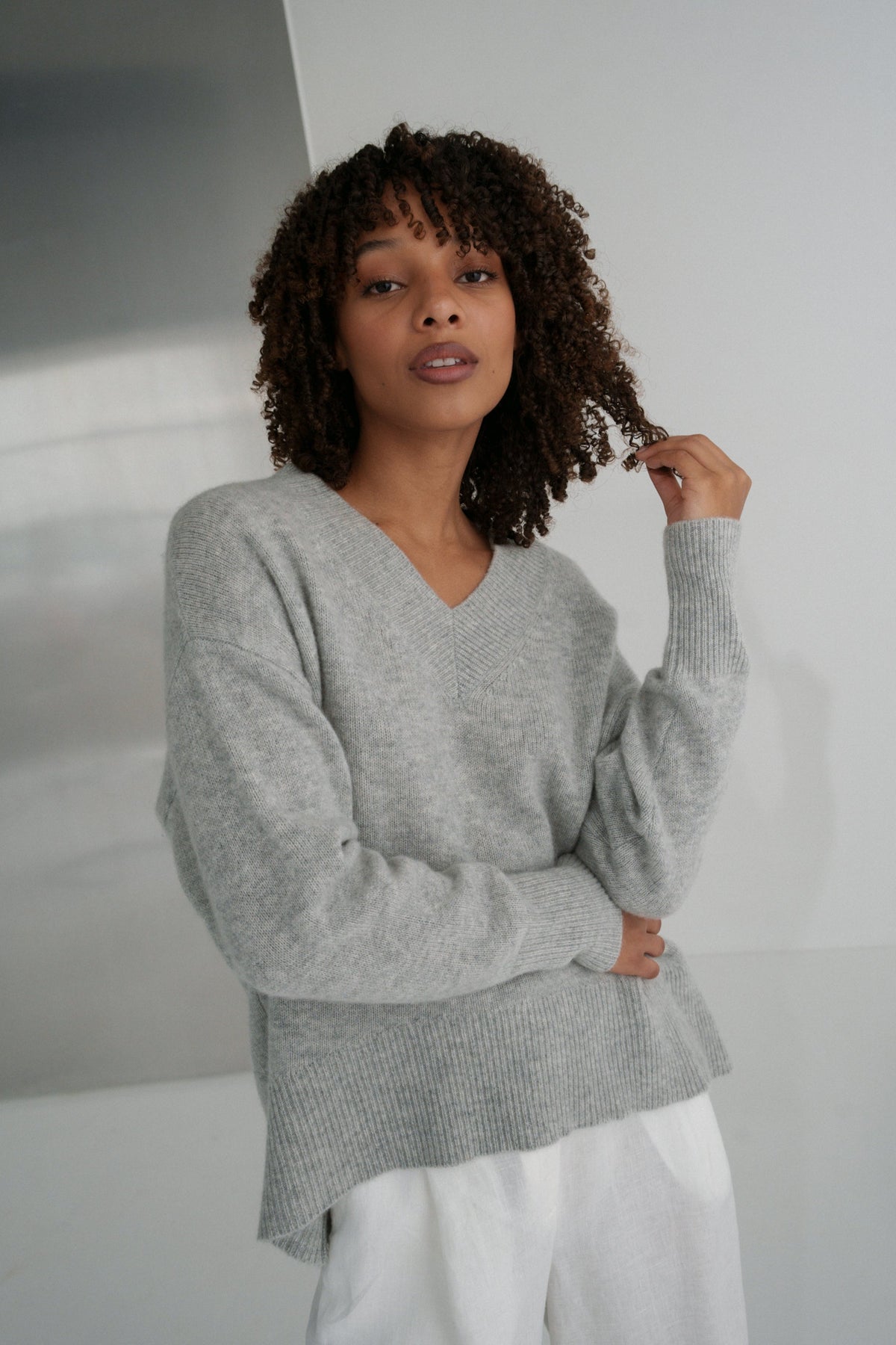 LILLY PILLY woman wearing an grey marle June cashmere knit and ivory linen pants in a minimalistic setting