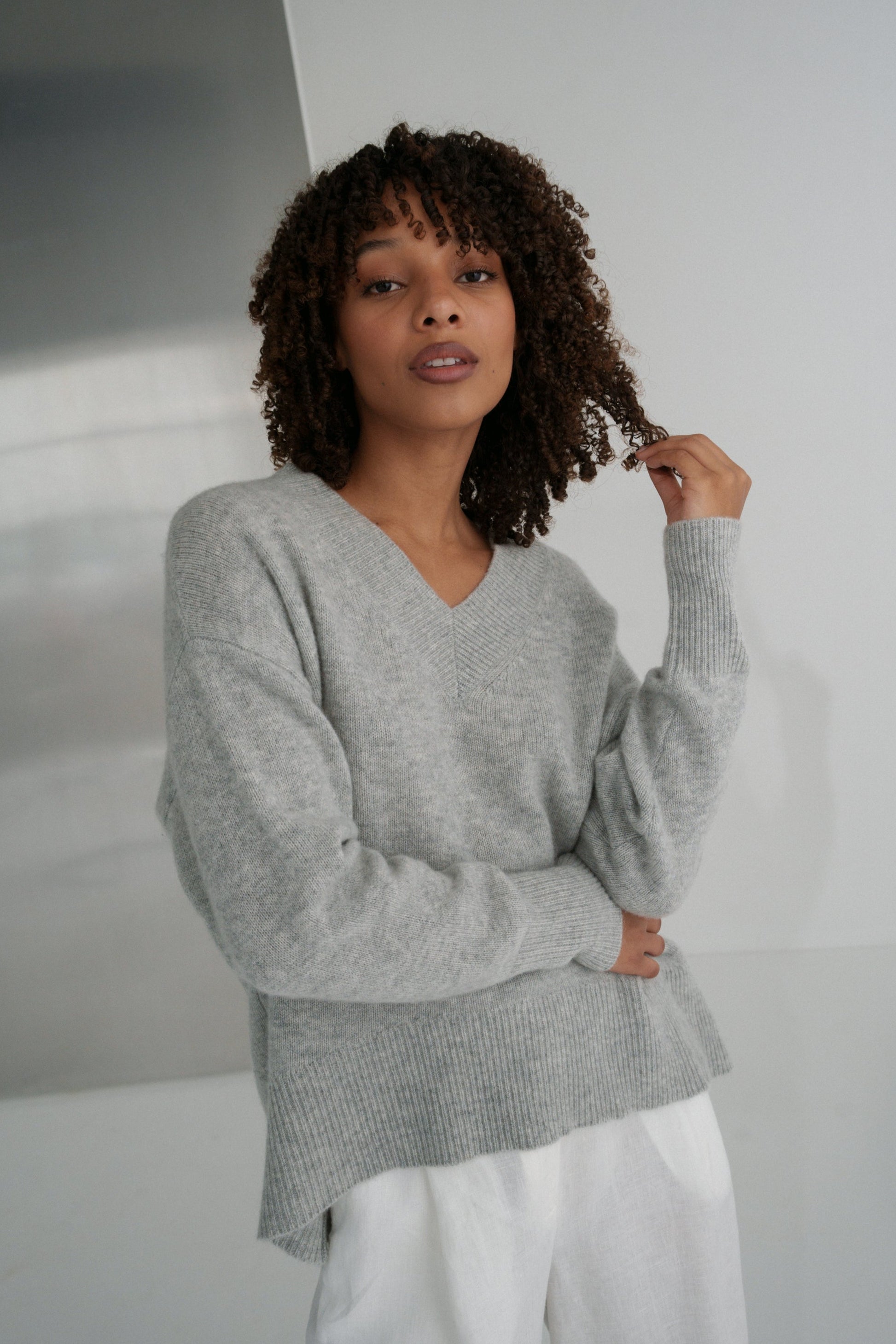 LILLY PILLY woman wearing an grey marle June cashmere knit and ivory linen pants in a minimalistic setting