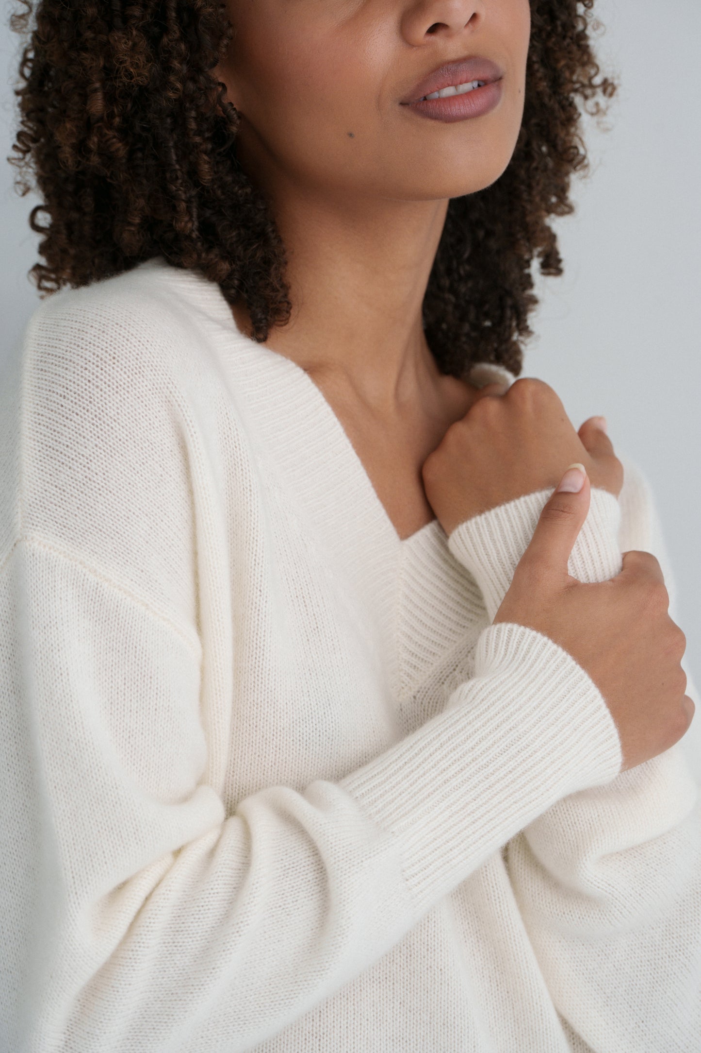 Close up of LILLY PILLY woman wearing an ivory June cashmere knit sweater against a plain background