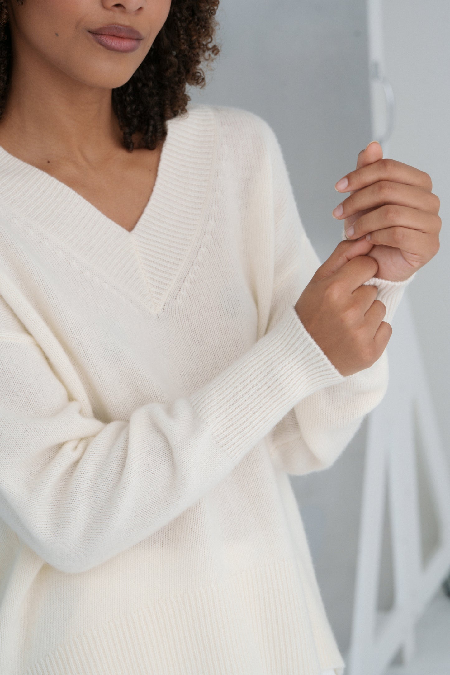Close-up of a LILLY PILLY woman wearing an ivory June cashmere knit sweater with a blurred background