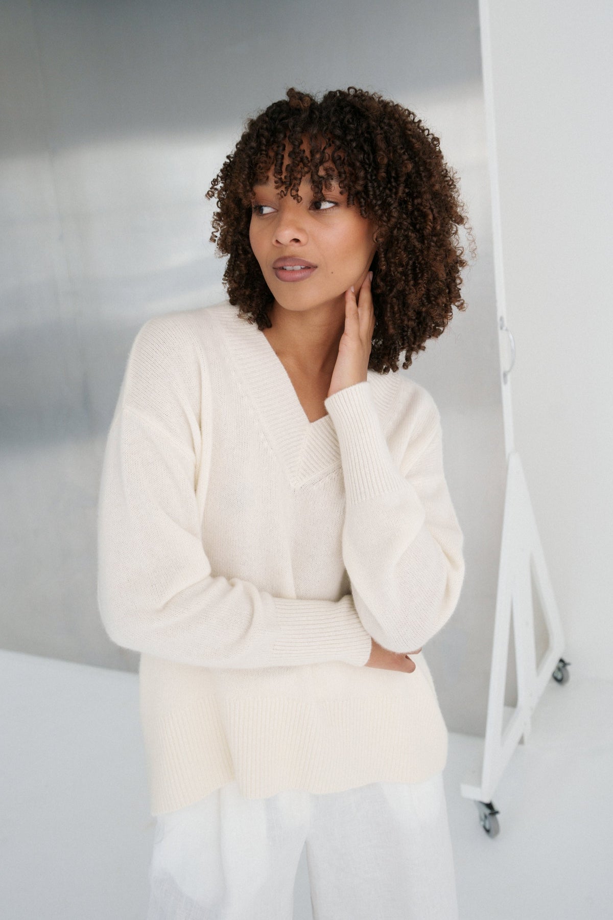 LILLY PILLY woman wearing an ivory June cashmere knit and pants in a minimalistic setting