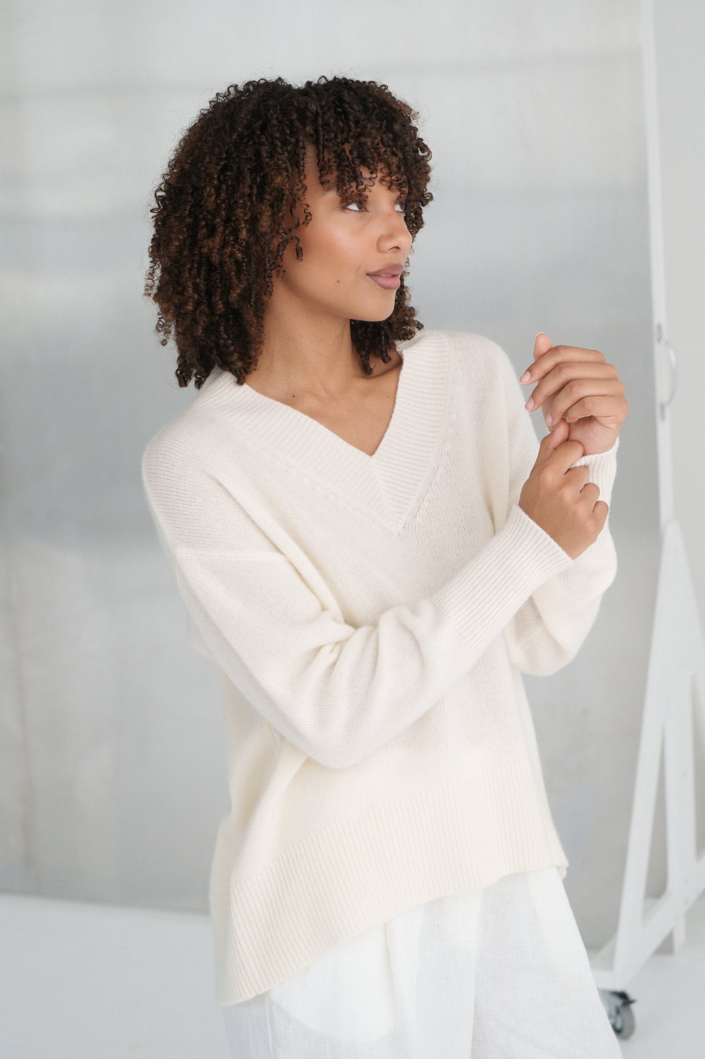 LILLY PILLY woman wearing an ivory June cashmere knit sweater against a plain background