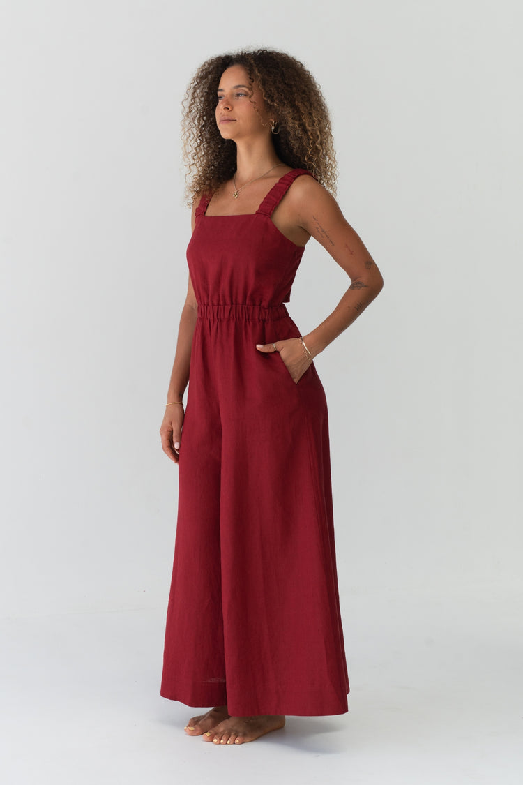 Side angle view of a woman wearing the Keely Linen jumpsuit in Cherry Red in a studio setting - Lilly Pilly Collection