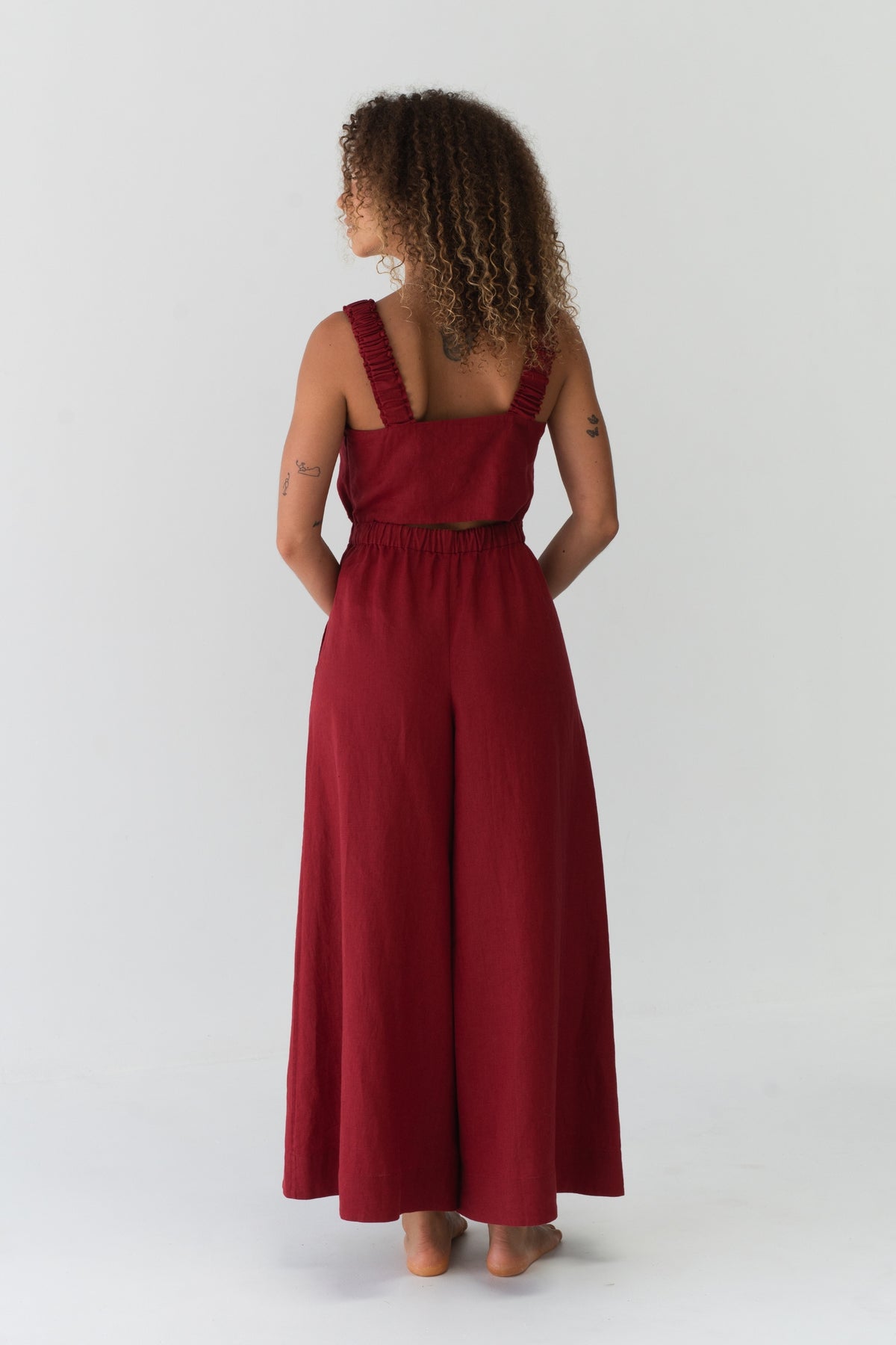 Back view of a woman wearing the Keely Linen jumpsuit in Cherry Red in a studio setting - Lilly Pilly Collection