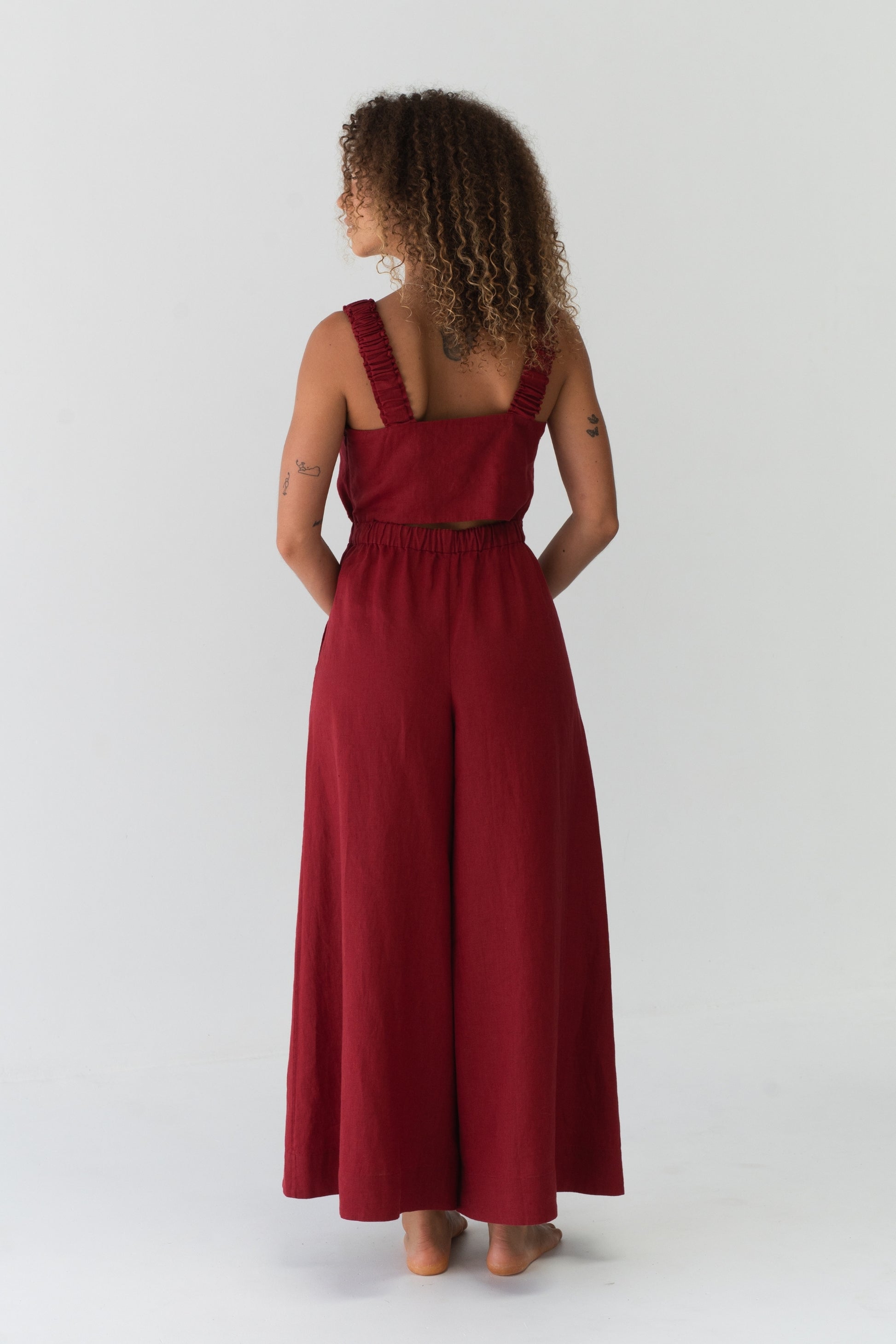 Back view of a woman wearing the Keely Linen jumpsuit in Cherry Red in a studio setting - Lilly Pilly Collection
