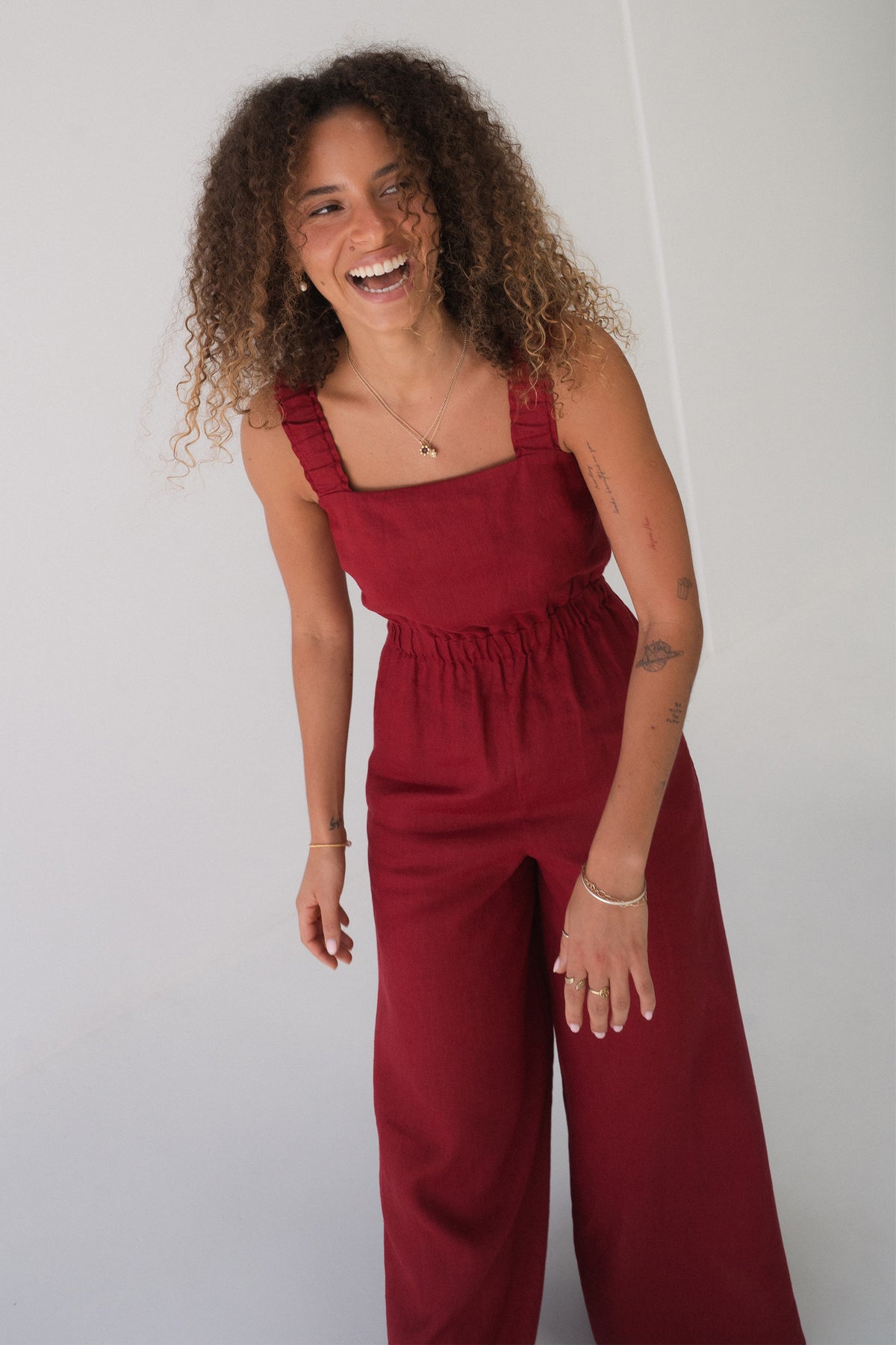 Front view of a woman laughing while wearing the Keely Linen jumpsuit in Cherry Red - Lilly Pilly Collection