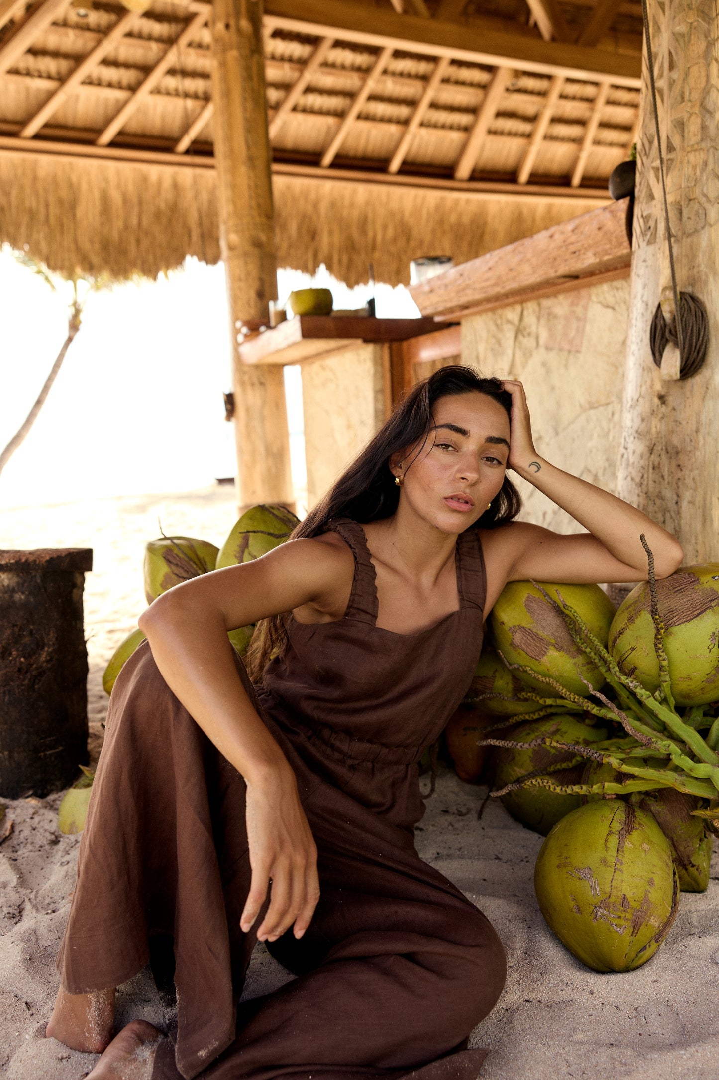 Seated woman wearing the Keely Linen jumpsuit in Chocolate - Lilly Pilly Collection
