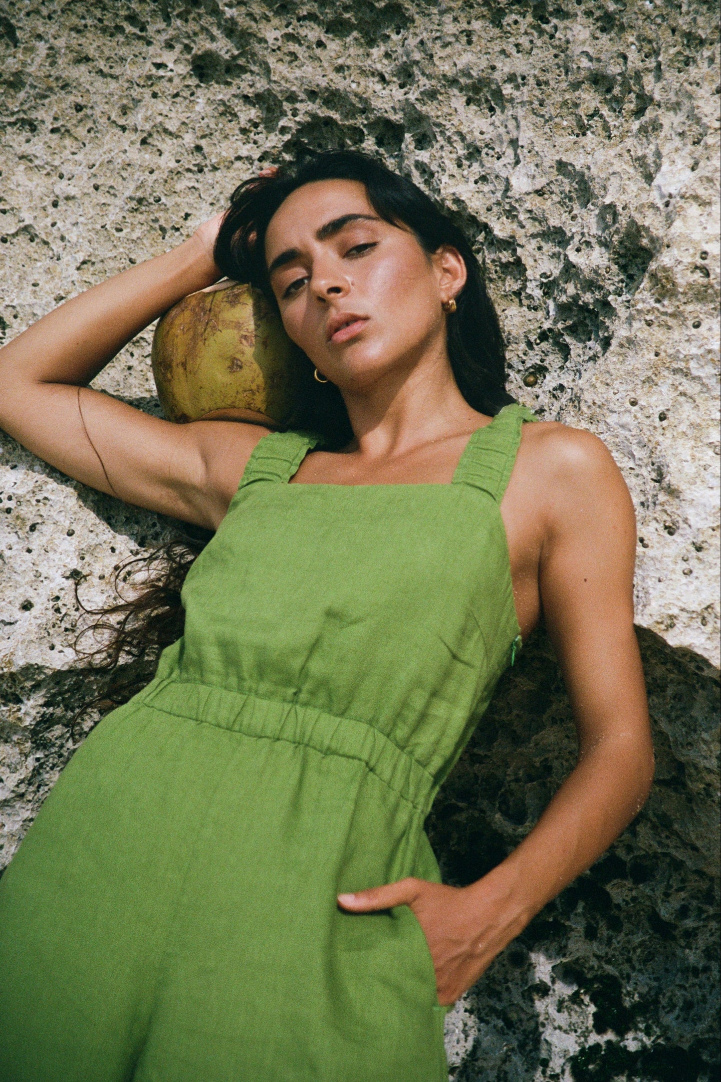 Keely Linen Jumpsuit in Lime Green - close up view while lying against a rock wall - Lilly Pilly Collection