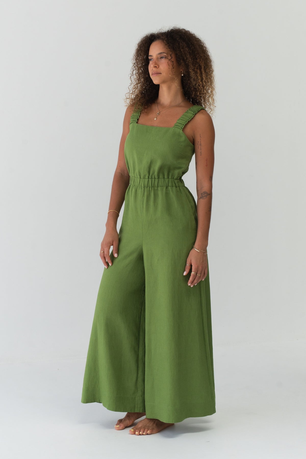 Side angle view of a woman wearing the Keely Linen jumpsuit in Lime Green - Lilly Pilly Collection